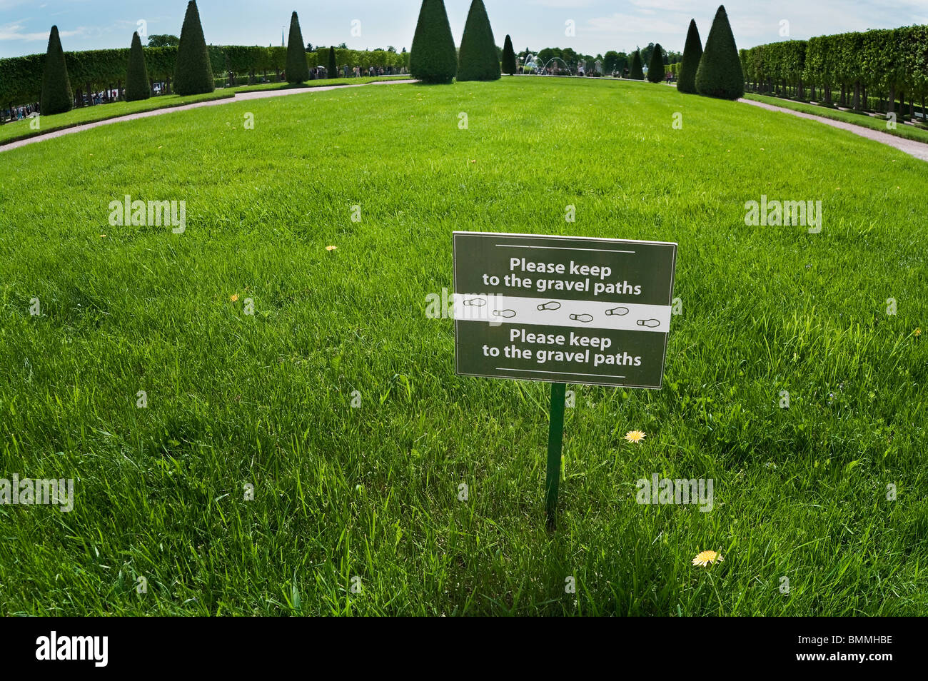 Bitte, halten Sie nicht Kiesweg. -Tag mit Hinweis auf dem grünen Rasen in Peterhof, St. Petersburg, Russland. Text auf Russisch und Englisch Stockfoto