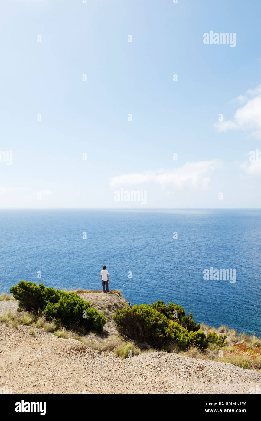 Mann am Rand einer Klippe auf der Suche auf See in Insel Faial, Azoren, Portugal Stockfoto