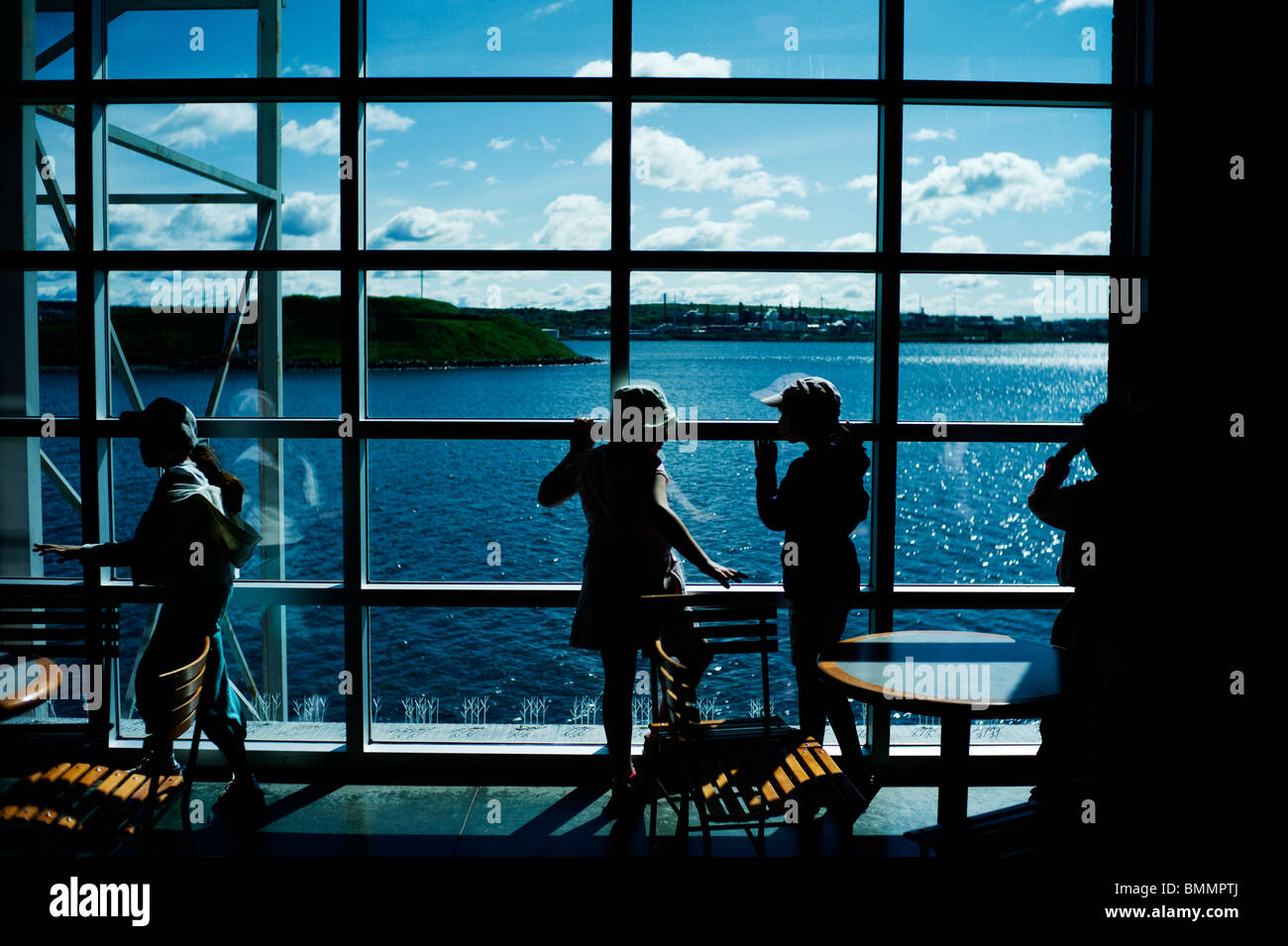 Junge Mädchen spielen vor große Fenster mit Blick auf Meer in Pier 21. Stockfoto