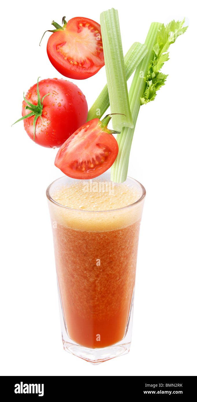 Scheiben von Tomaten und Sellerie fallen in ein Glas frischen Orangensaft Stockfoto