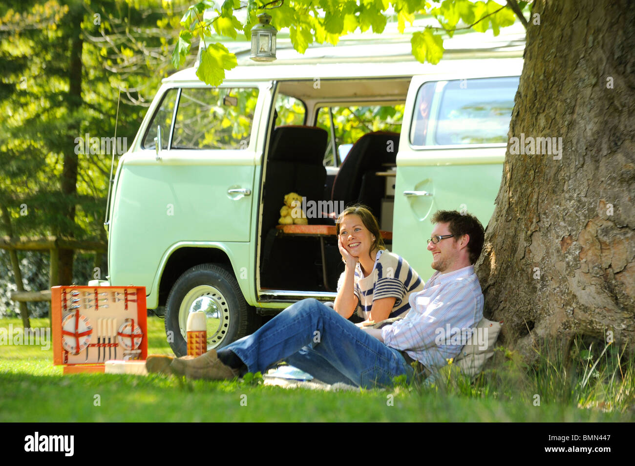 Ein junges Paar genießt einen Campingurlaub in einem klassischen VW-Wohnmobil. Stockfoto