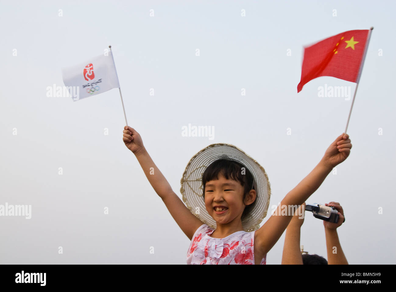 Kind, wehende Fahnen bei der Feier der Olympischen Spiele 2008 in den Straßen von Peking, China. Asien Stockfoto
