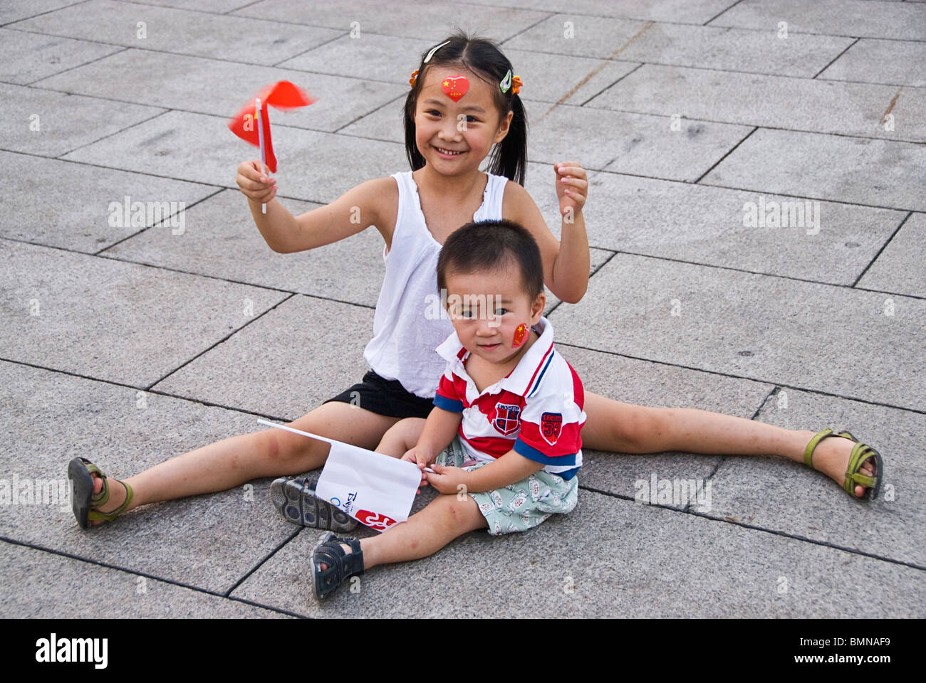 Kinder wehende Fahnen bei der Feier der Olympischen Spiele 2008 in den Straßen von Peking, China. Asien Stockfoto