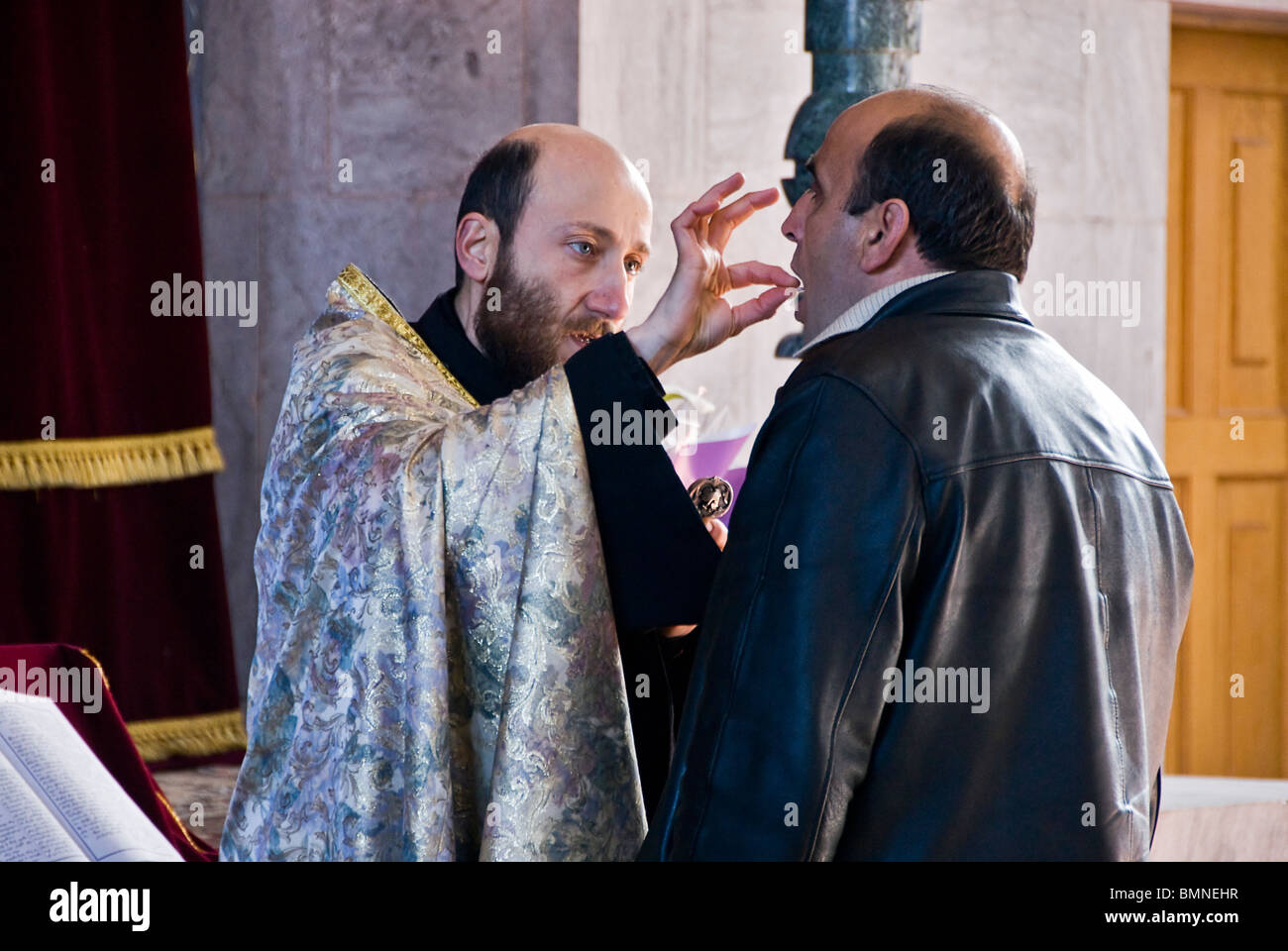 Priester taufte einen erwachsenen Mann in einer orthodoxen Kirche in Armenien. Stockfoto