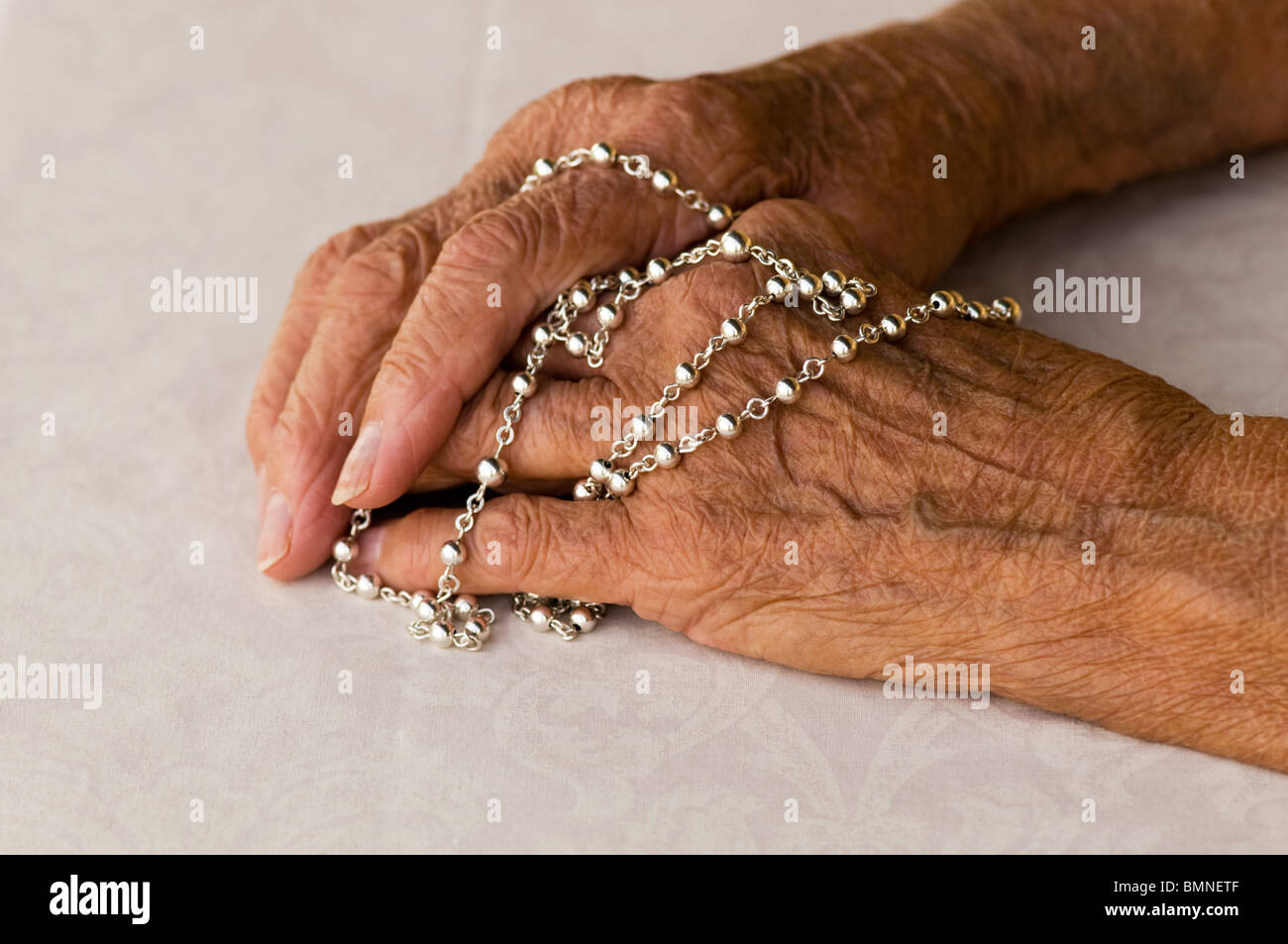 Nahaufnahme der Frau mit ihren Rosenkranz beten Stockfoto