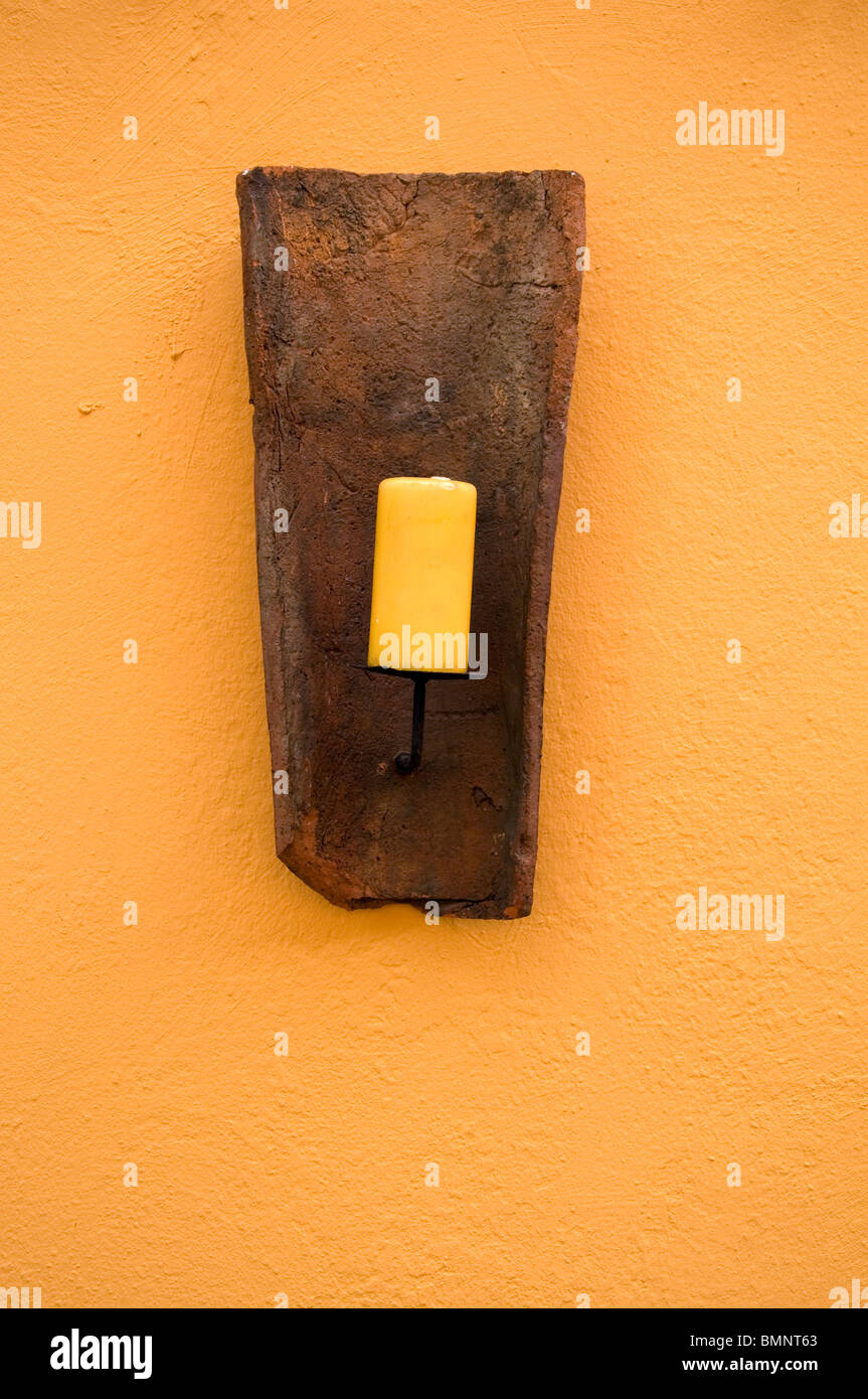 gelbe Kerze vor einer gelben Wand Stockfoto