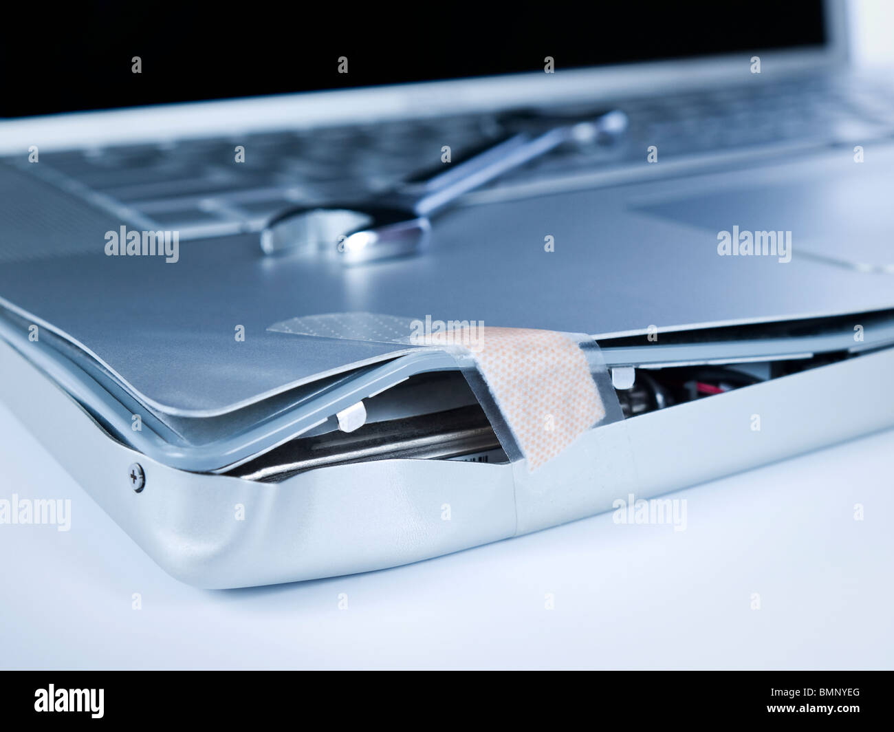 Ein Pflaster ist einen beschädigte Laptop reparieren. Ein Schraubenschlüssel ist über den Computer. Stockfoto