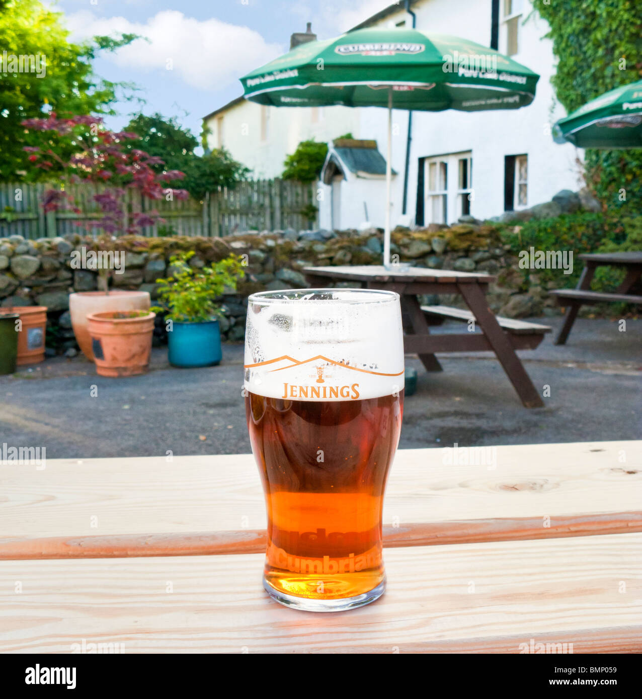 Pint Bier auf einem Gartentisch Bier in einem Pub in der Seenplatte, UK - Jennings Cumbrian ale Stockfoto