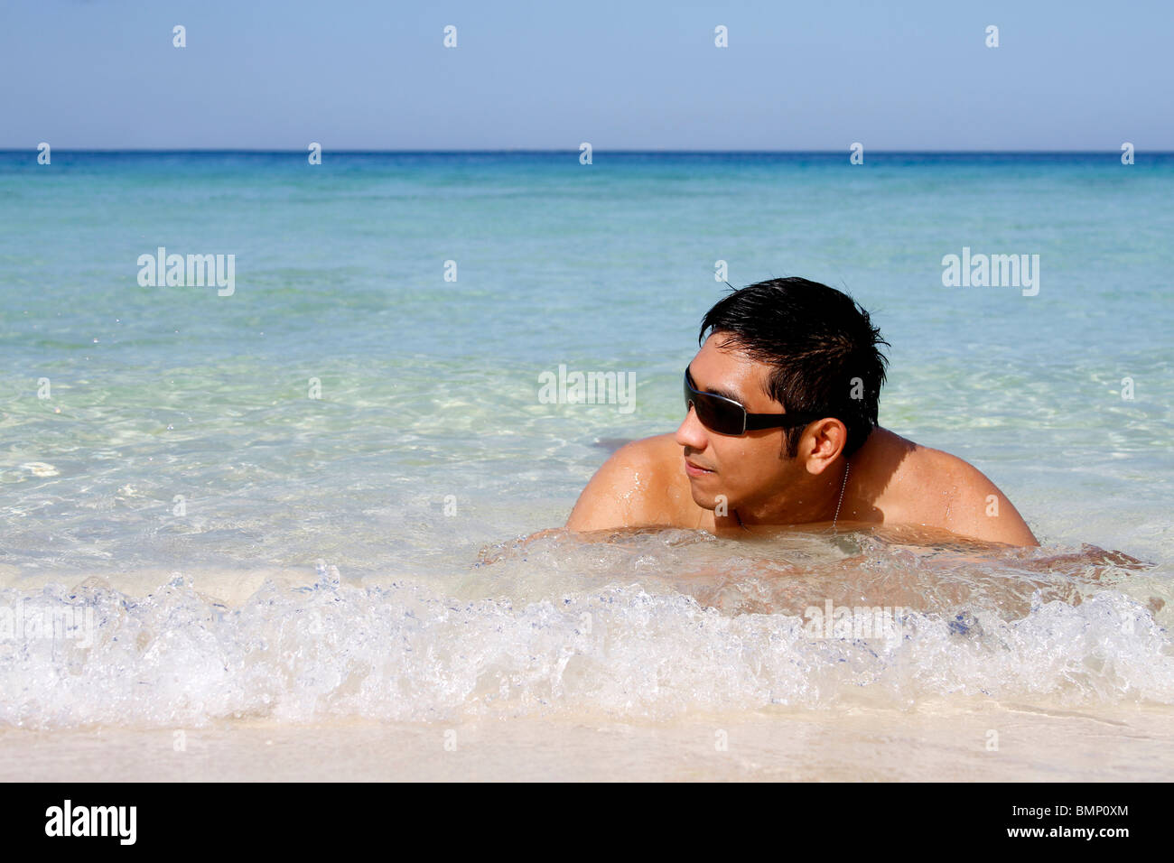 Mann mit Sonnenbrille entspannen direkt am Strand Stockfoto