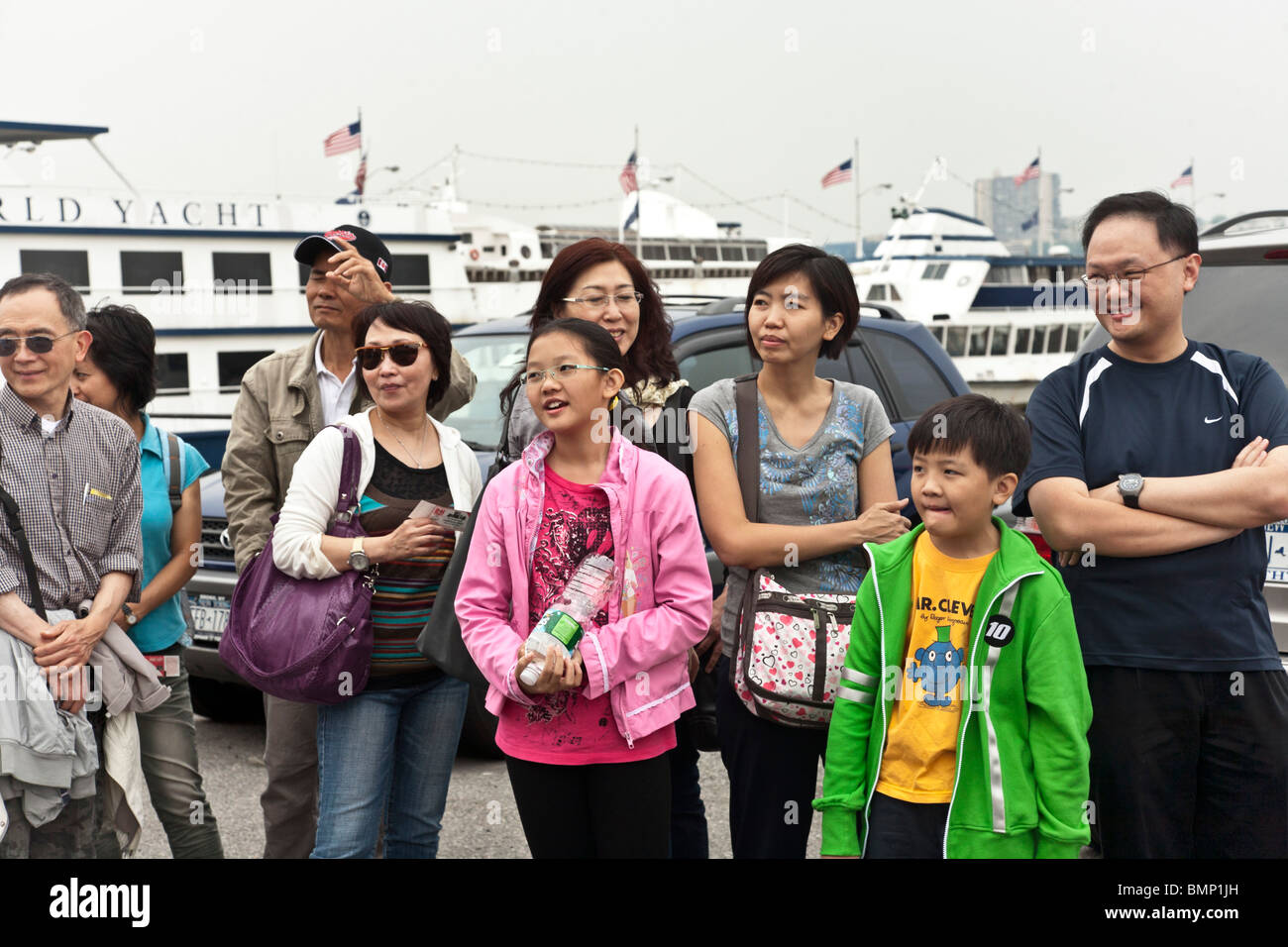 Happy Chinese American Familiengruppe Uhren Entertainer während der Wartezeit in der Warteschlange für Circle Line Tour von New York harbor Stockfoto
