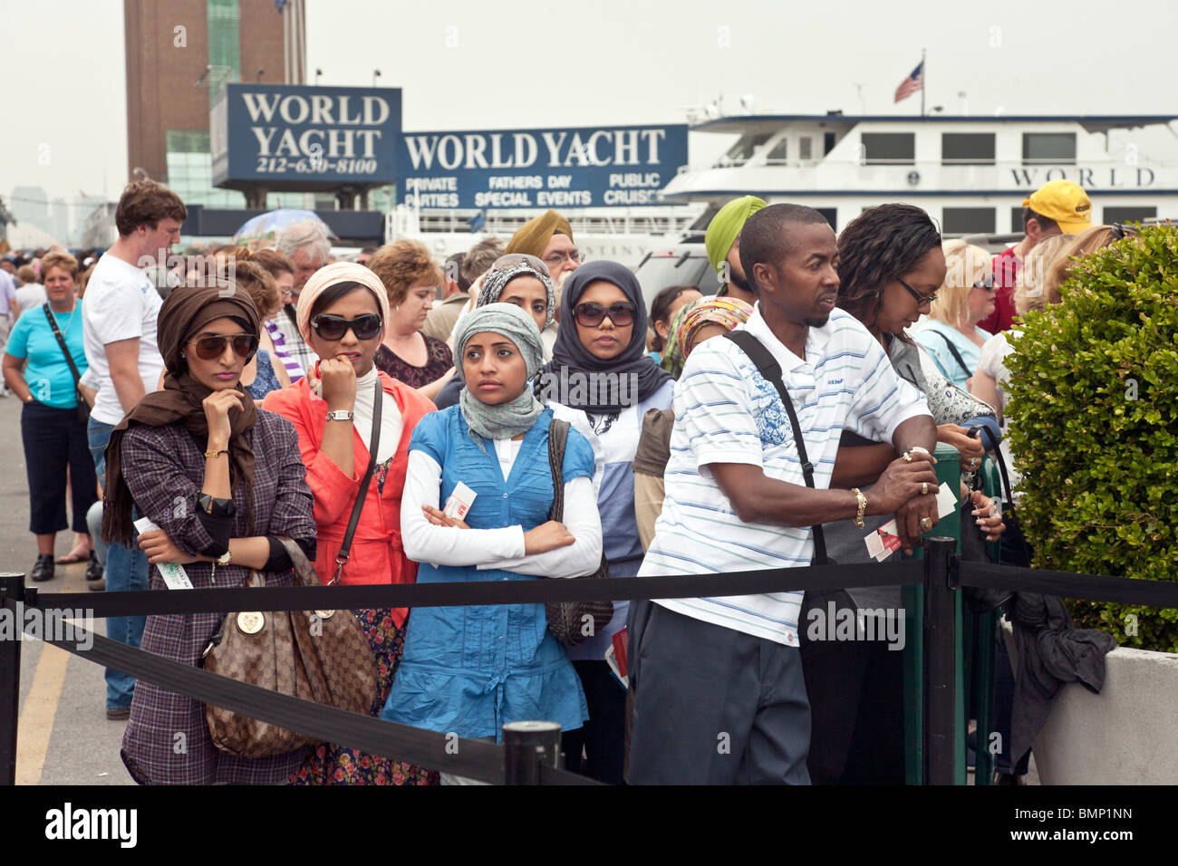 vier junge muslimische Freundinnen holen Kopftücher Kopftuch warten in langen Schlange für die Circle Line Tour von New York harbor Stockfoto
