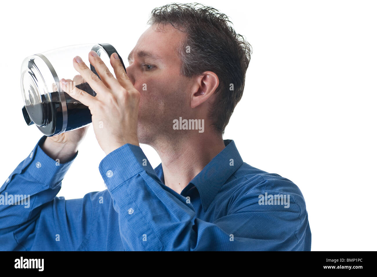 Ein Mann in einem blauen Kleid Shirt, trinken aus einer Kaffeekanne, isoliert auf weiss. Stockfoto