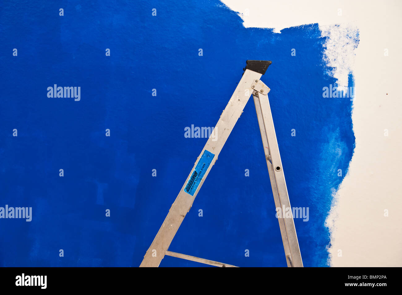 eine Trittleiter und eine unvollendete blau gestrichenen Wand Stockfoto