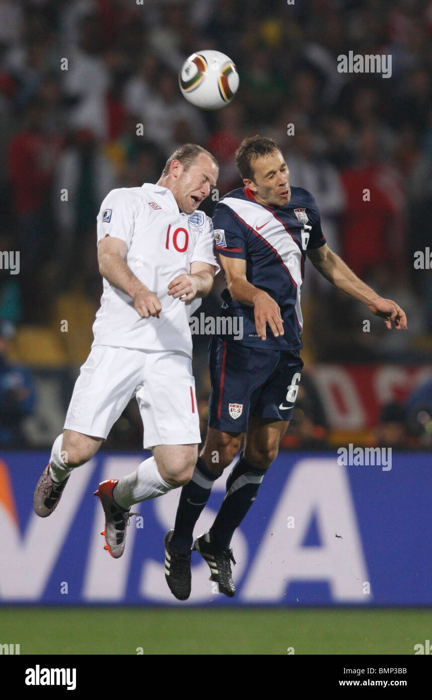 Wayne Rooney von England (l) und Steve Cherundolo von der USA (r) wetteifern um einen Header während eines Fußballspiels 2010 World Cup. Stockfoto
