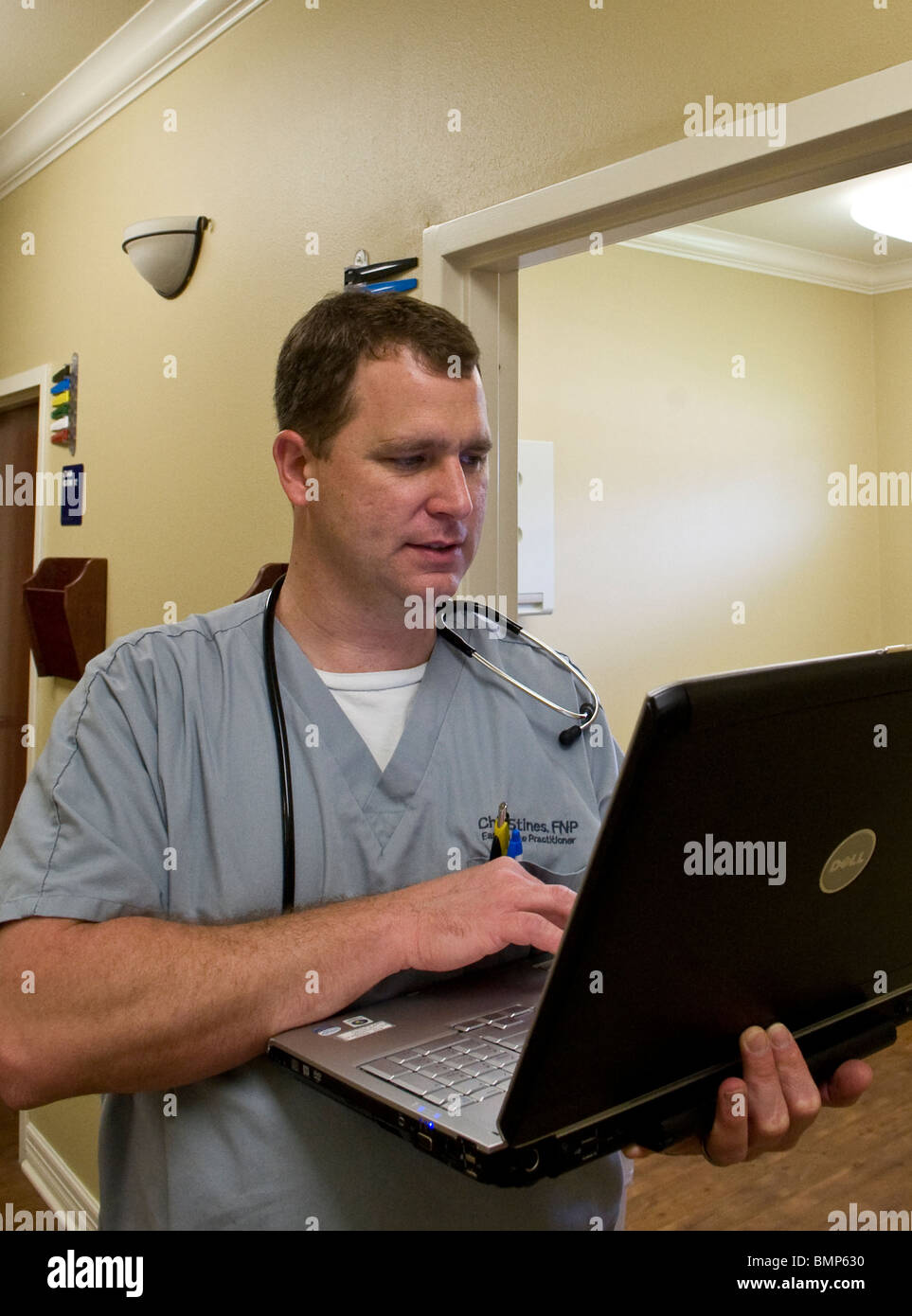 Männliche Krankenschwesterpraktiker in Victoria, Texas, USA, prüft Hinweise auf seinem Laptopcomputer, bevor man ein Patient in seinem Büro. Stockfoto