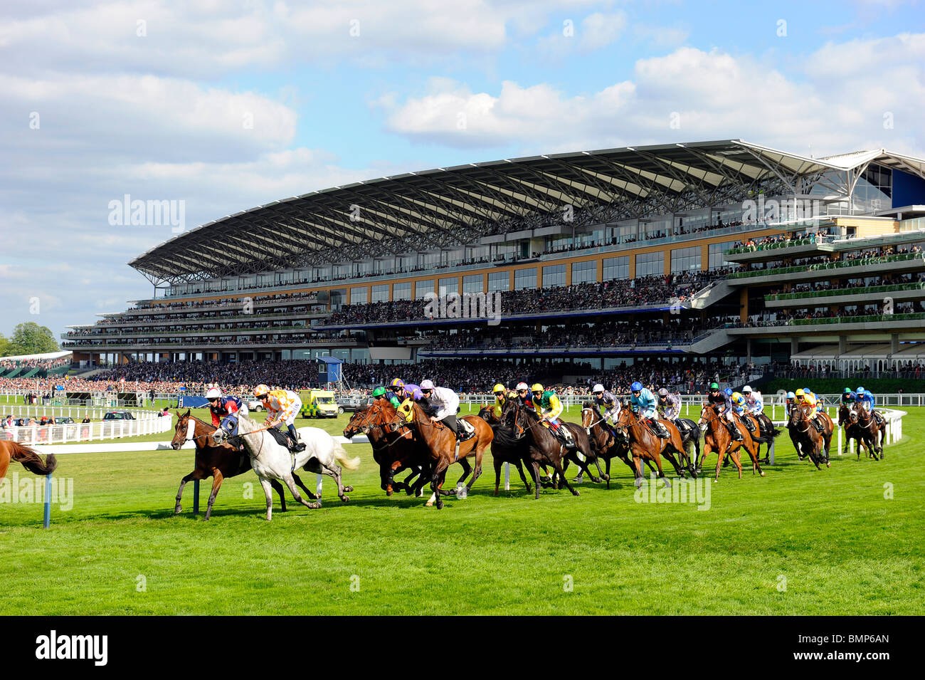 Pferde Rennen um die Kurve mit der Tribüne im Hintergrund während der Tag eins des Royal Ascot 2010 Stockfoto