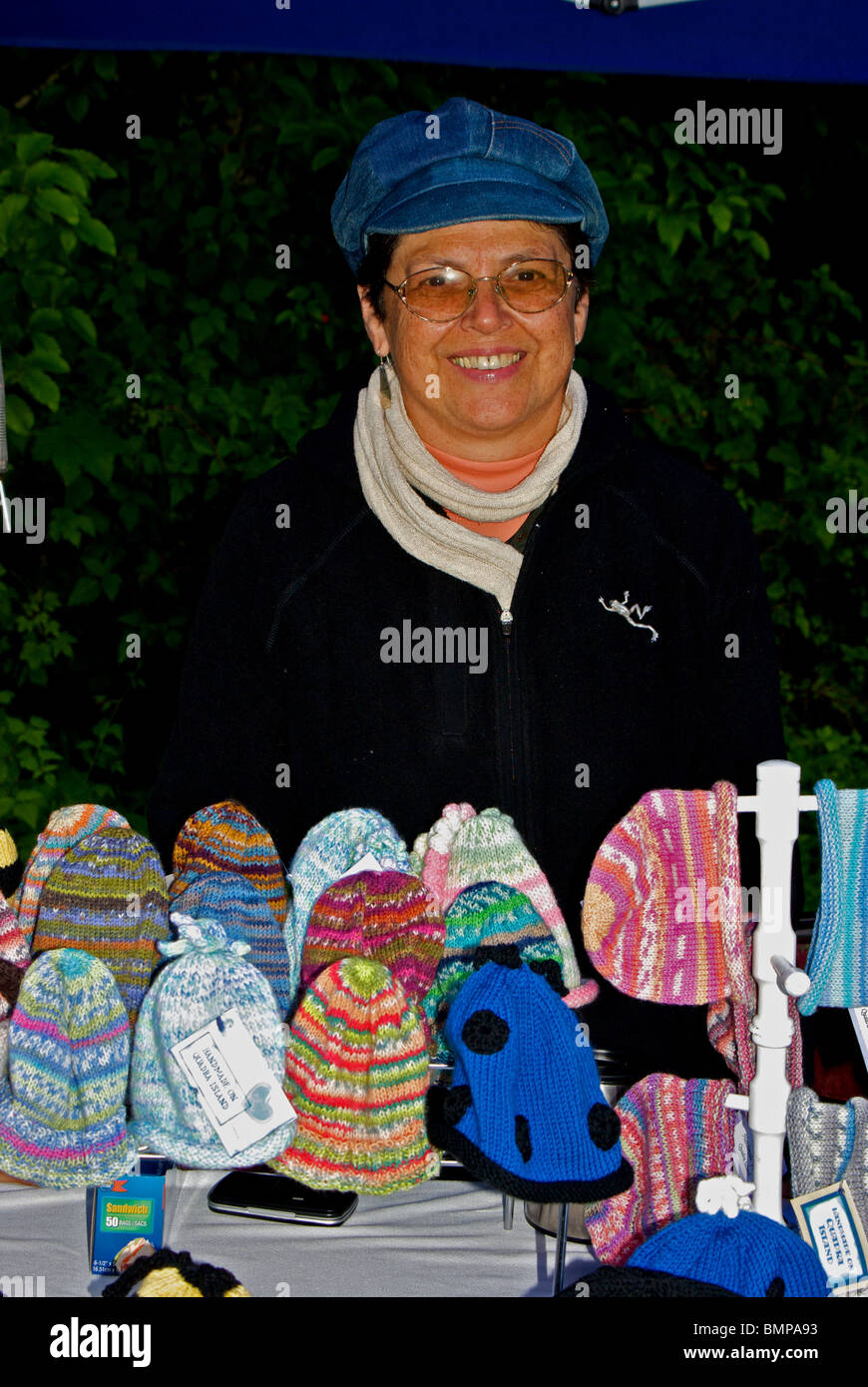 Strickerin Anzeigen von Hand gestrickt Hauben Mützen bei der wöchentlichen Samstag Quadra Island BC Bauer Markt und Bazar Stockfoto