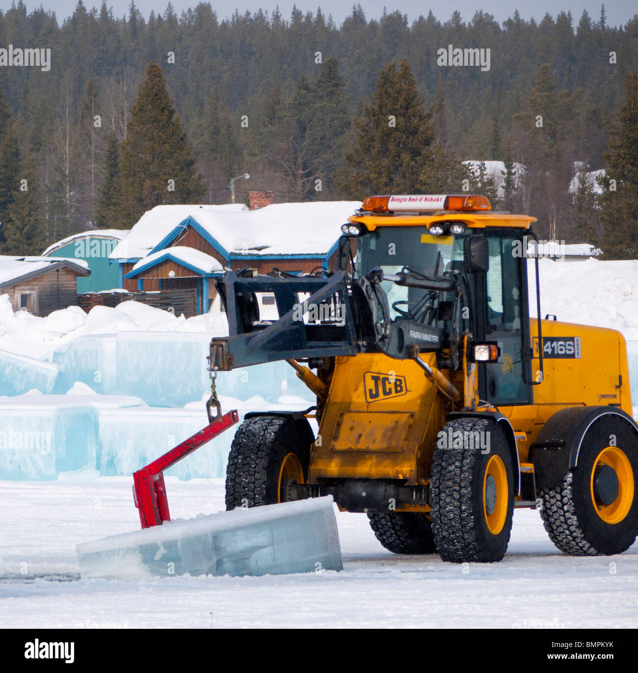 Große Eisblöcke werden geschnitten und aus dem gefrorenen Torne Älv Fluss mit schwerem Gerät in Jukkasjärvi Icehotel herausgehoben. Stockfoto