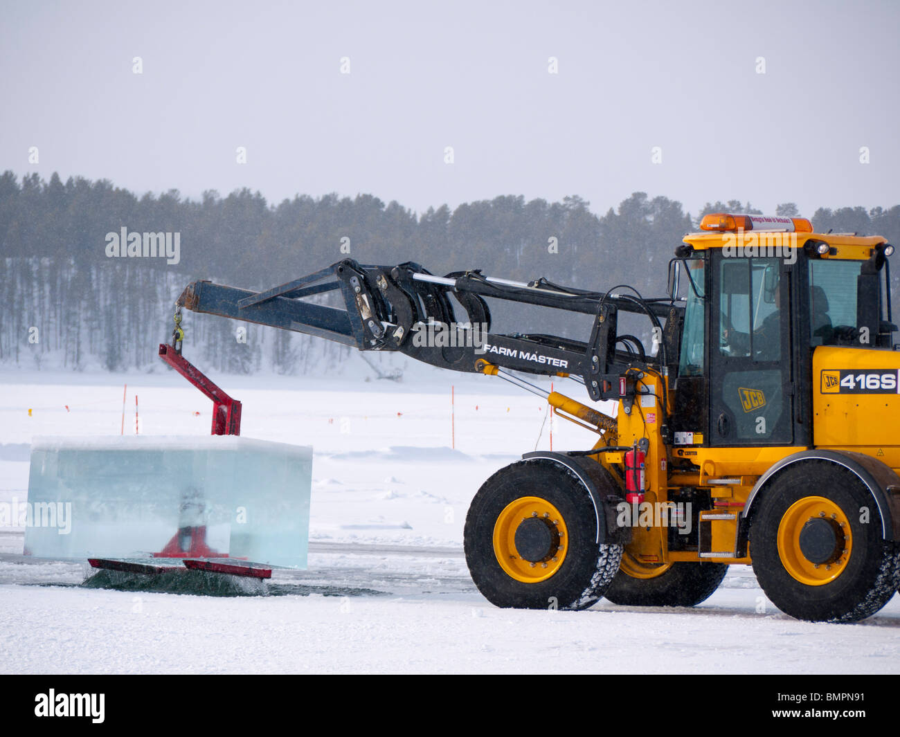 Große Eisblöcke werden geschnitten und aus dem gefrorenen Torne Älv Fluss mit schwerem Gerät in Jukkasjärvi Icehotel herausgehoben. Stockfoto