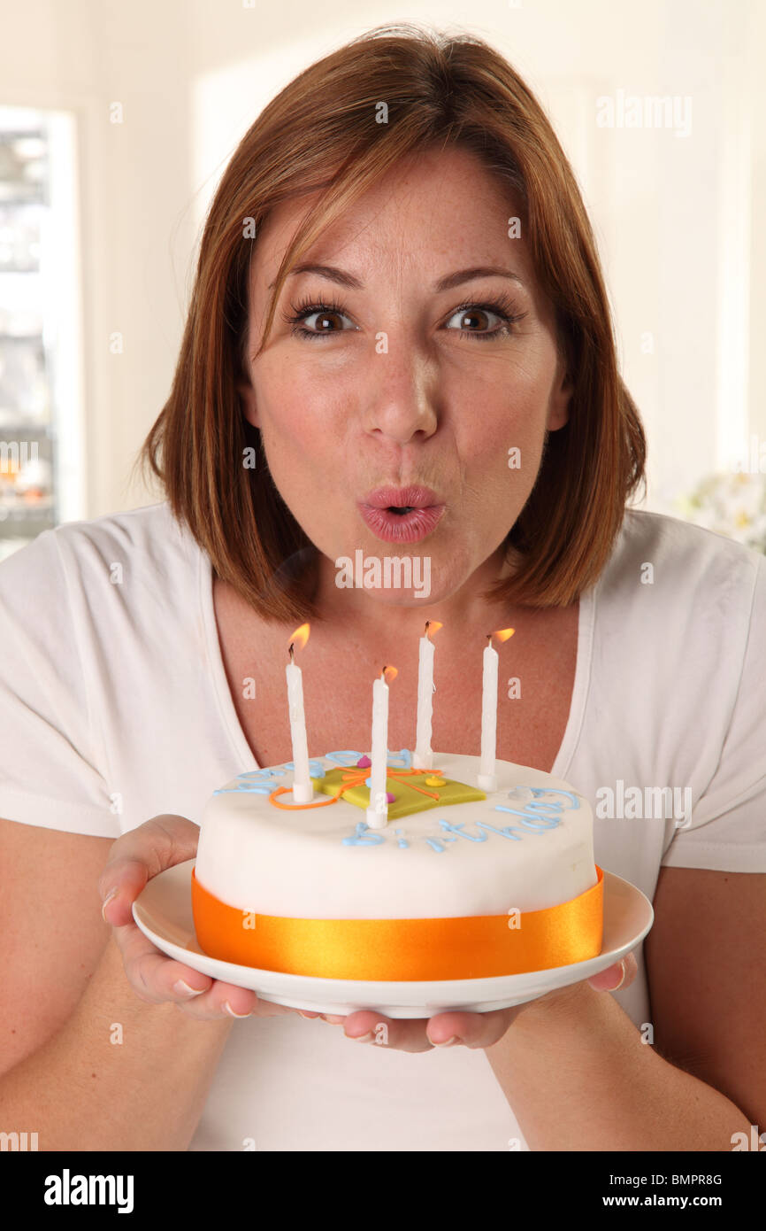 FRAU AUSBLASEN DER KERZEN AUF DER GEBURTSTAGSTORTE Stockfoto