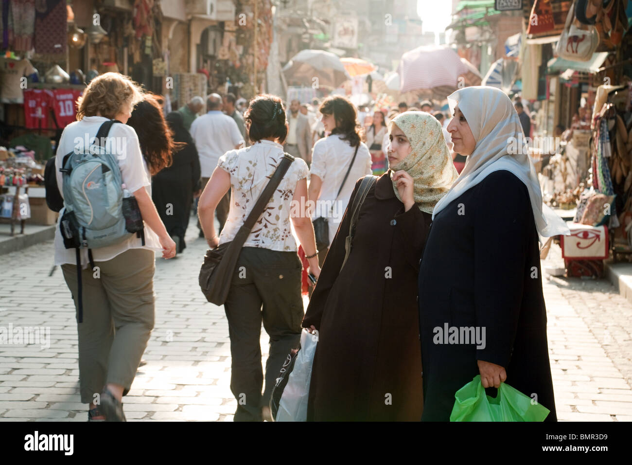Kulturkontrast; westliche Touristen und lokale muslimische arabische Frauen auf dem multikulturellen Khan al Khalili Markt, dem islamischen Viertel, Kairo, Ägypten, Afrika Stockfoto