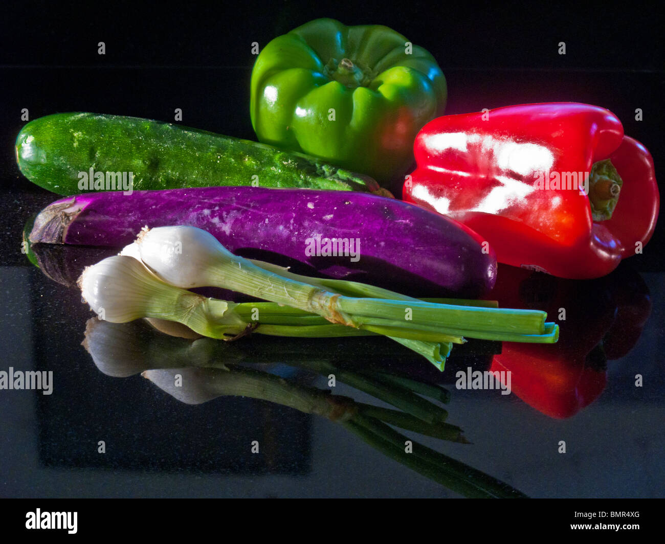 Eine japanische Aubergine, Zucchini Kürbis, grüne und rote Paprika und ein paar Frühlingszwiebeln bilden ein Stillleben in der Nachmittagssonne. Stockfoto