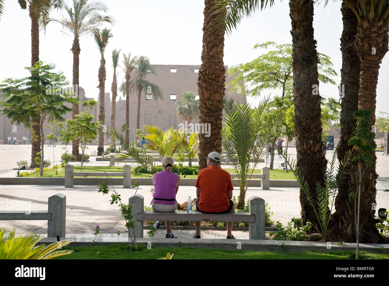 Touristen sitzen in den Gärten außerhalb der ersten Pylon, der Eingang zum Karnak Tempel, Luxor, Ägypten Stockfoto
