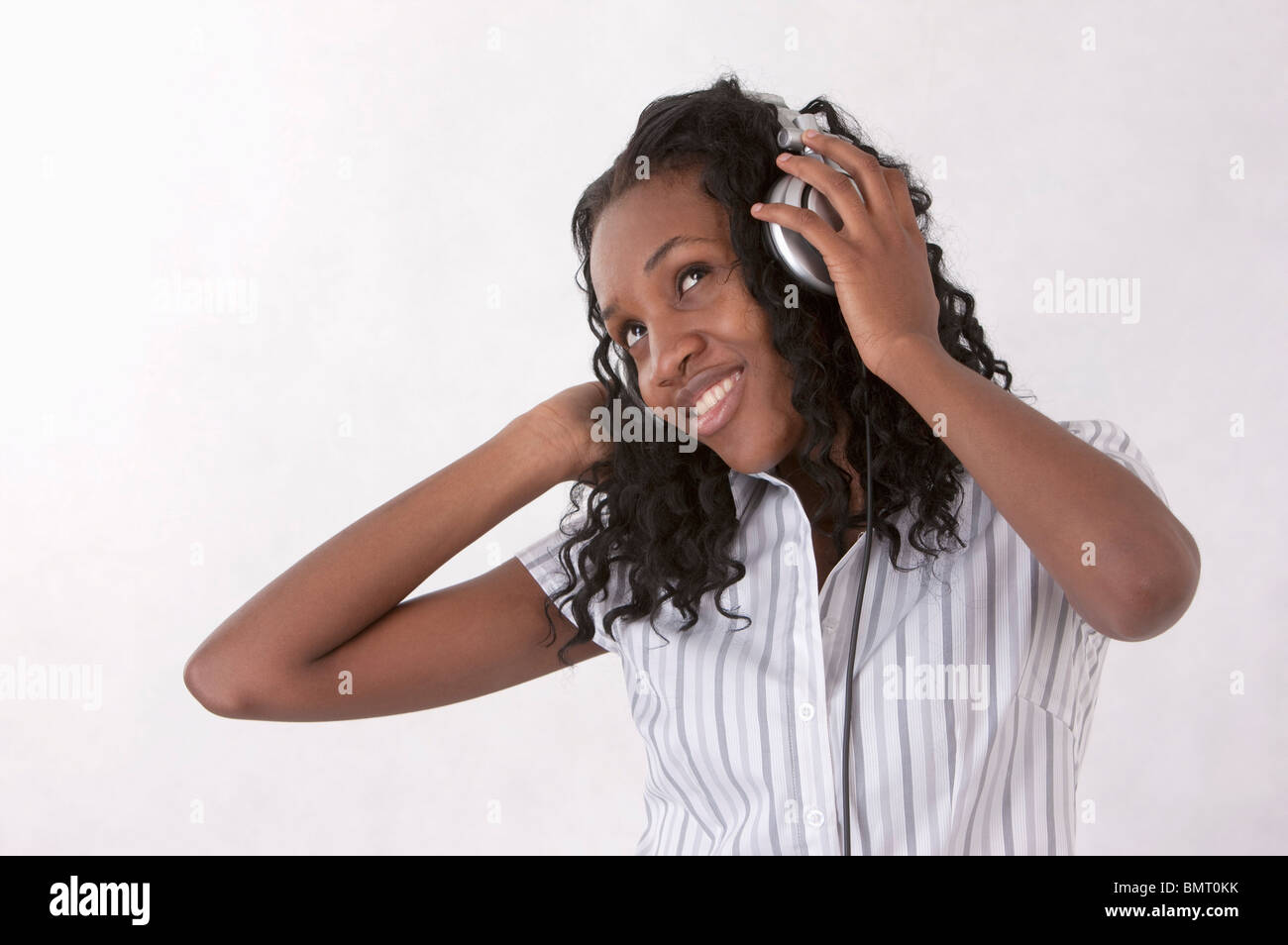 Junge Frau mit Lächeln nachschlagen und Musik mit Kopfhörer hören Stockfoto