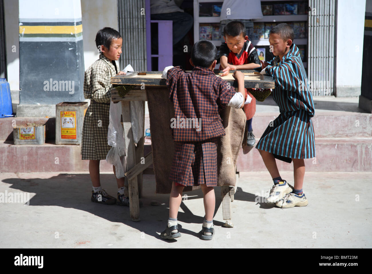 Eine Gruppe von vier jungen aufgeregt spielen das beliebte lokale Brettspiel Carrom in der Straße Paro, Bhutan. Stockfoto