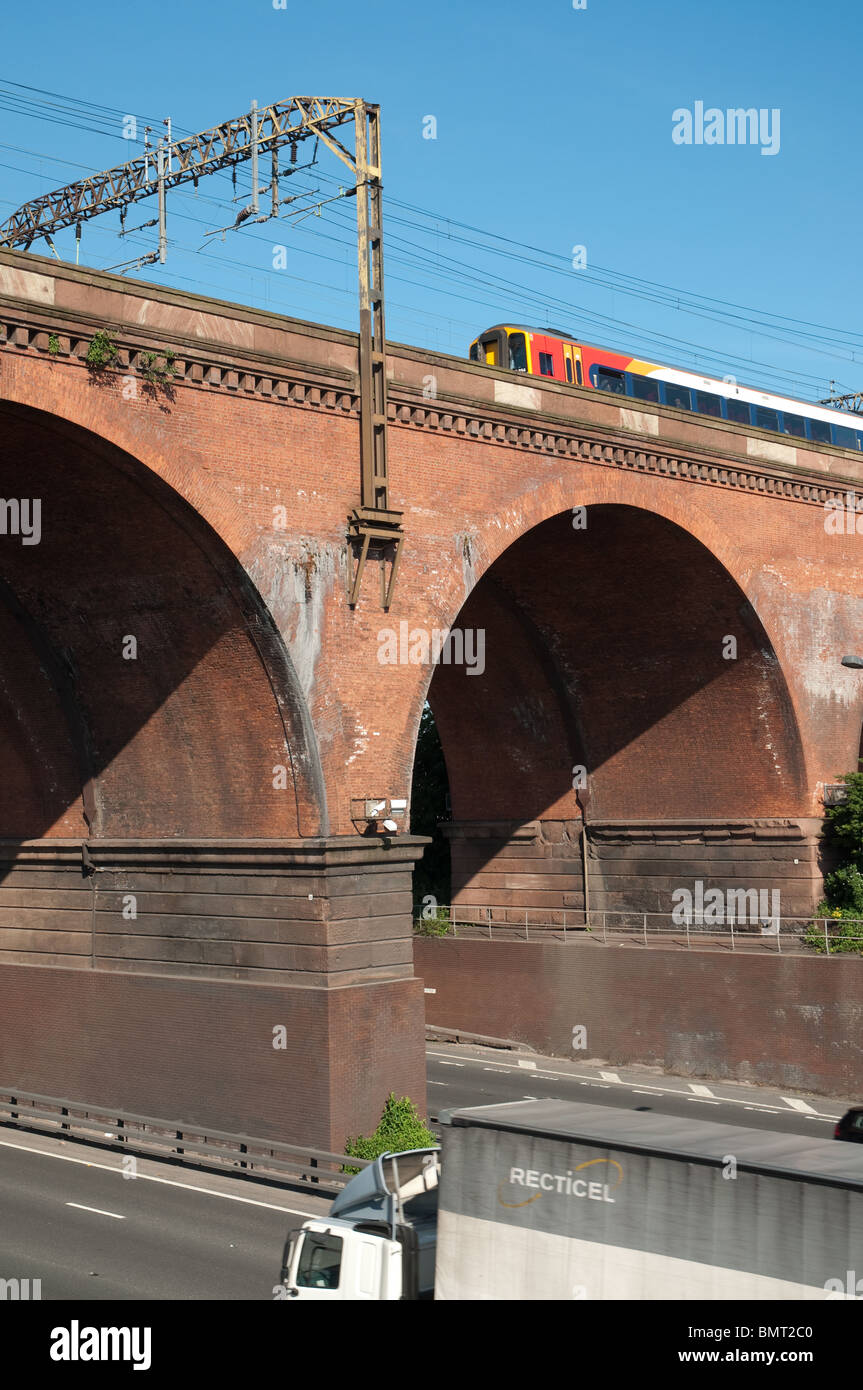 Zug fährt in Stockport Viadukt mit Autobahn M60. Stockfoto
