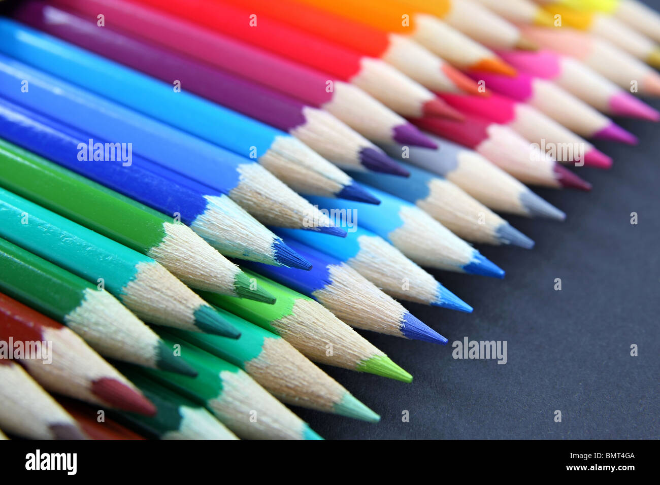 Bunte Bleistifte in einer Reihe auf schwarzem Hintergrund isoliert Stockfoto