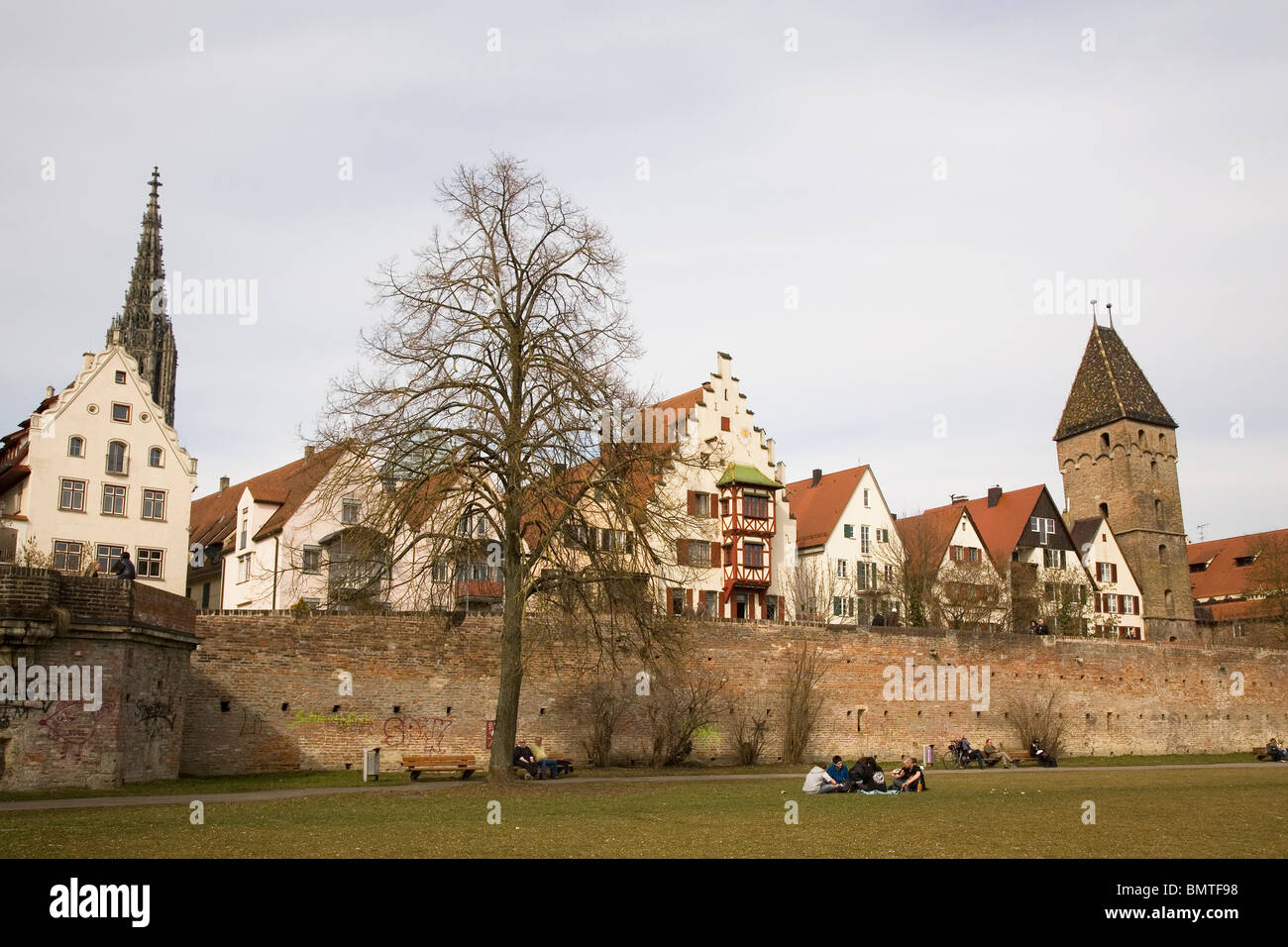 Die Menschen genießen das Grün unter den historischen Stadtmauern, in der Nähe der Metzgerturm (Fleischer Turm) in Ulm, Baden-Württemberg. Stockfoto