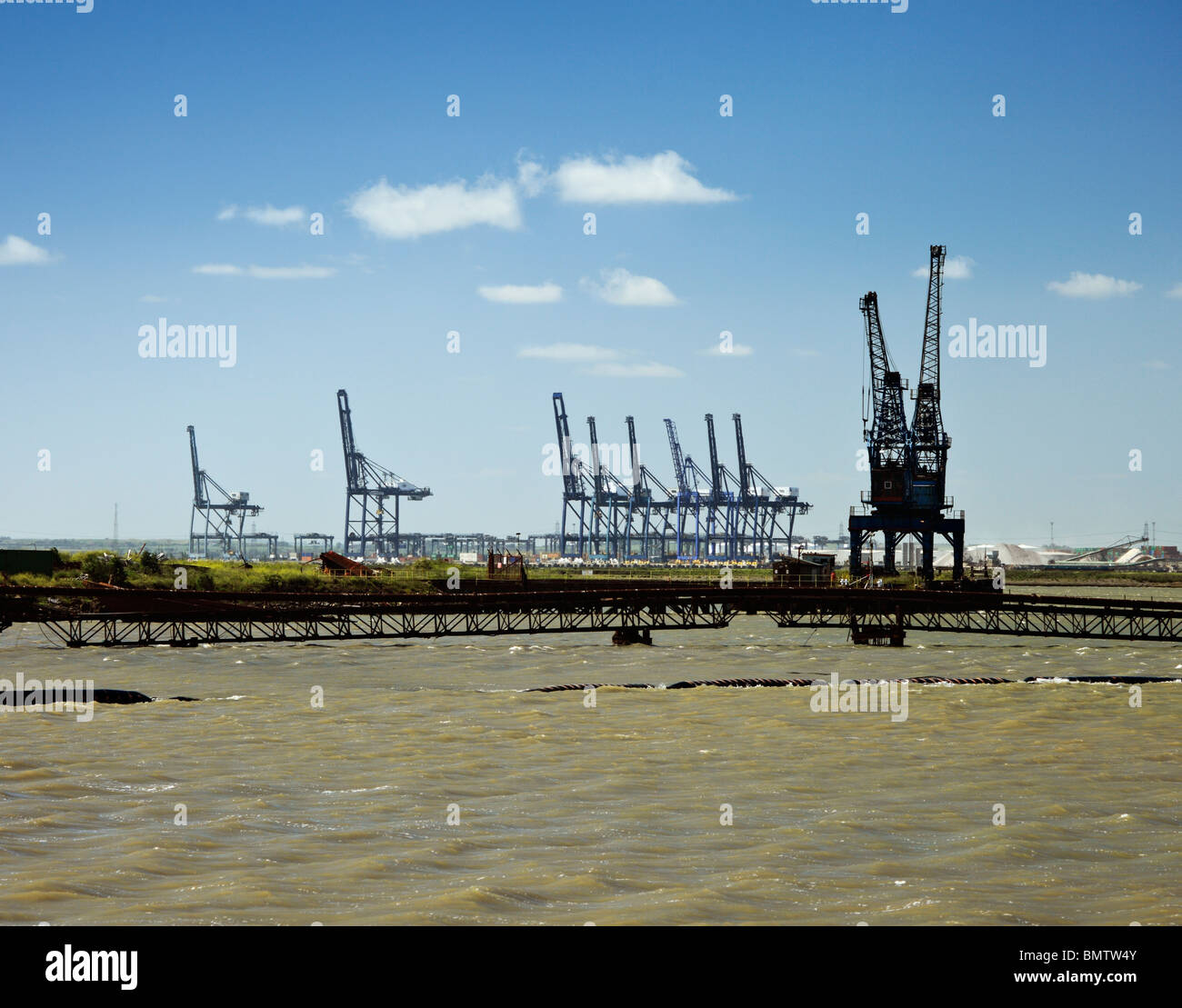 Stillgelegten Industrieareal im Kohle-Waschanlagen Wharf, Sheppey. Mit London Thamesport Kräne im Hintergrund. Stockfoto