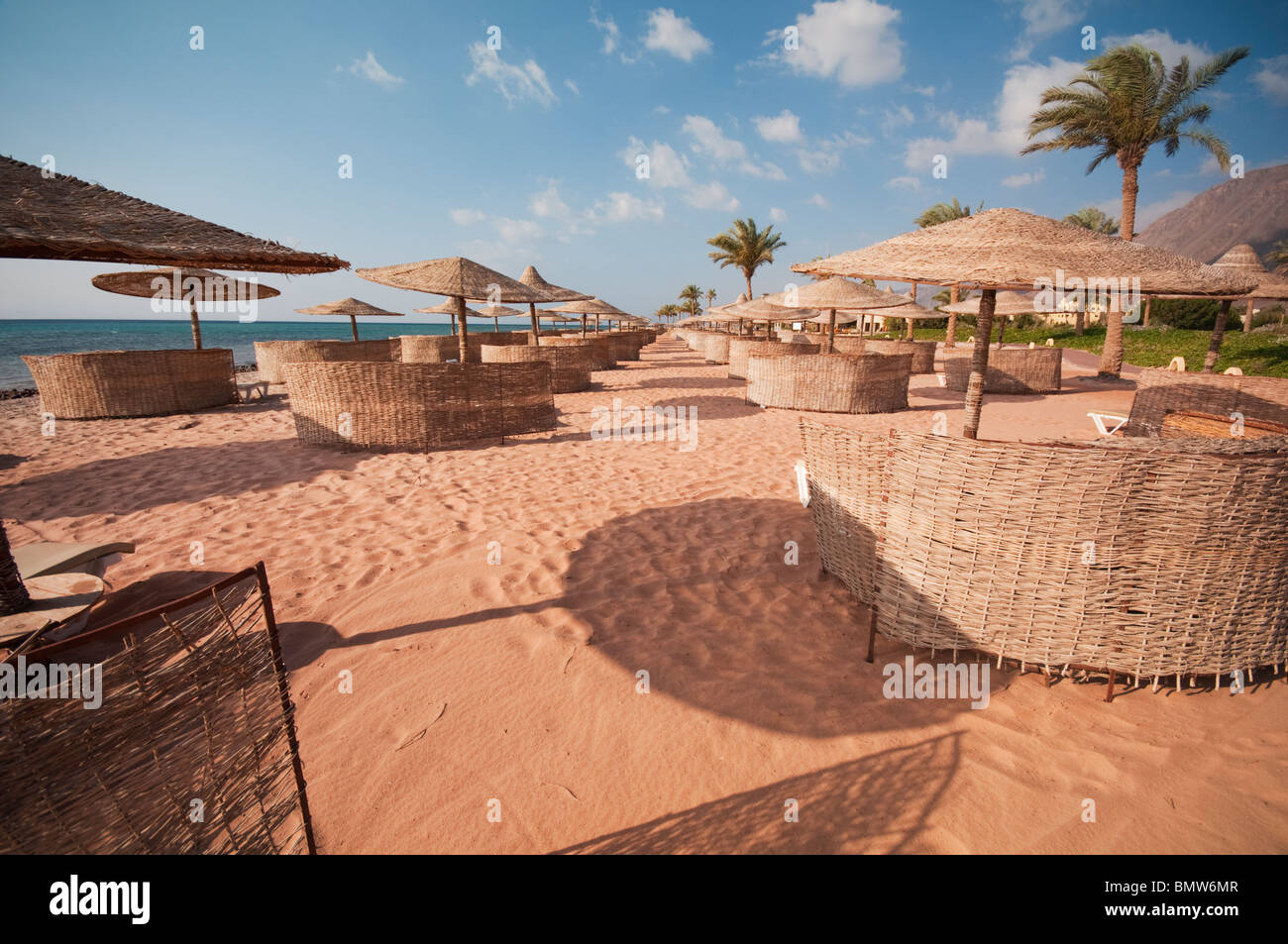 Eine wunderschönen Urlaub Szene voller Sand und Sonnenschirmen geschützt durch Wicker Windbreaker gekrönt von von einem unglaublich blauen Himmel. Stockfoto