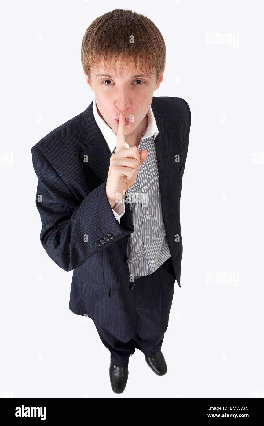 Junger Geschäftsmann nachschlagen und Lippen Finger aufsetzen Stockfoto