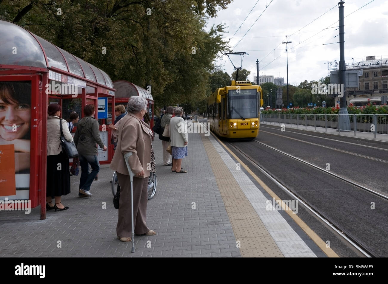 Polnischen Menschen warten auf die Straßenbahn zu stoppen, mit gelben Straßenbahn nähert, öffentliche Verkehrsmittel, Warschau, Polen, EU Stockfoto