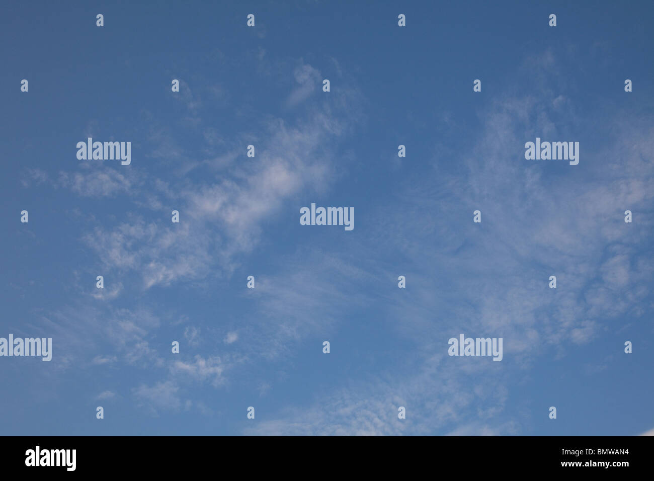 Weiße Wolkenfetzen machen Muster vor einem blauen Himmel an einem späten Sommerabend am längsten Tag des Jahres in Nordengland Stockfoto