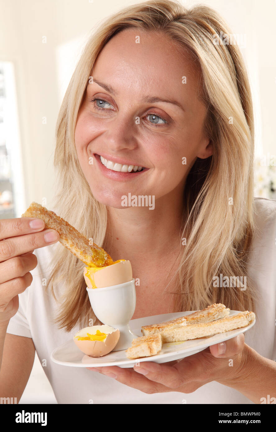 FRAU, EIN GEKOCHTES EI ZU ESSEN Stockfoto