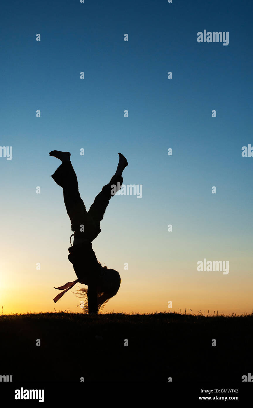 Young Girl energetisch Spaß macht einen Handstand bei Sonnenuntergang. Silhouette Stockfoto