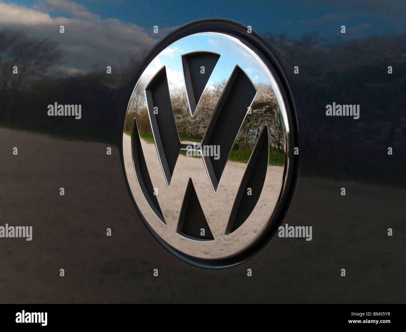 Nahaufnahme von einem Chrome Volkswagen VW-Logo auf einem Auto mit Reflexionen Stockfoto