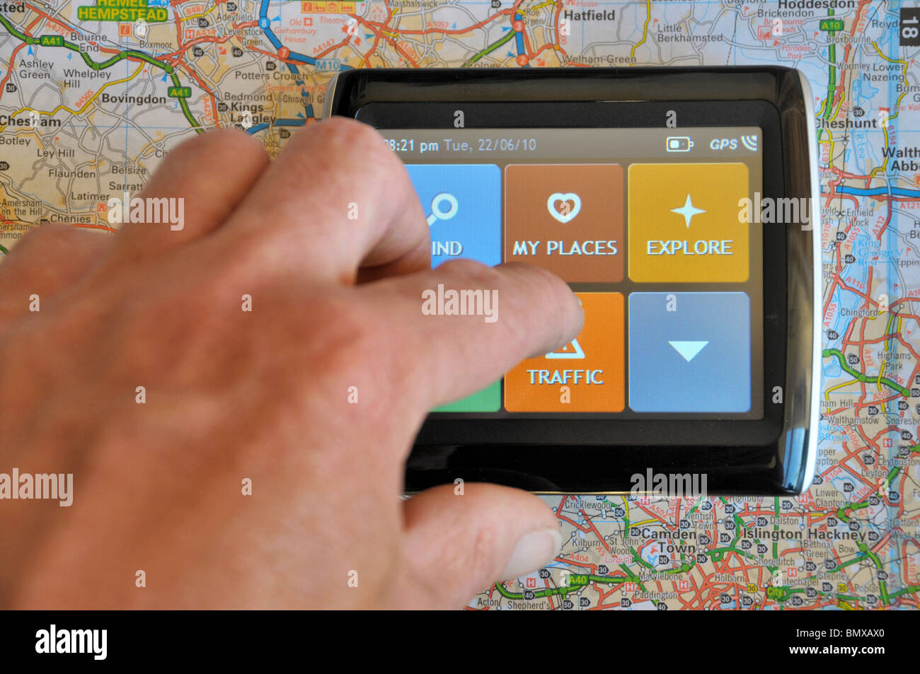 ein Navi sitzt auf einer Straßenkarte mit einer Hand über den Touchscreen, um Informationen zum Straßenverkehr zu finden. Stockfoto
