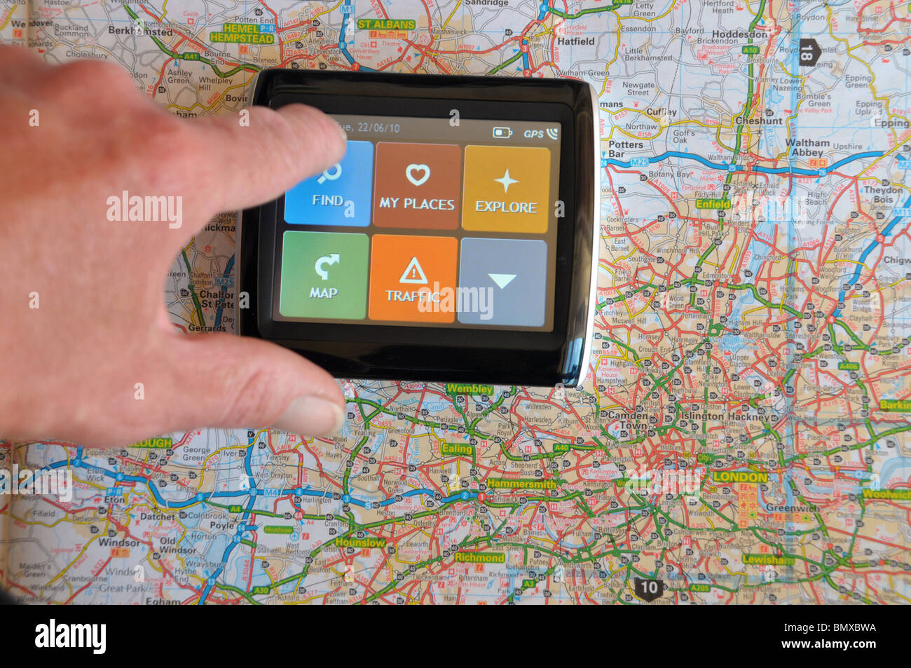 ein Navi sitzt auf einer Straßenkarte mit einer Hand über den Touchscreen ein 'Find' Ziel angeben. Stockfoto