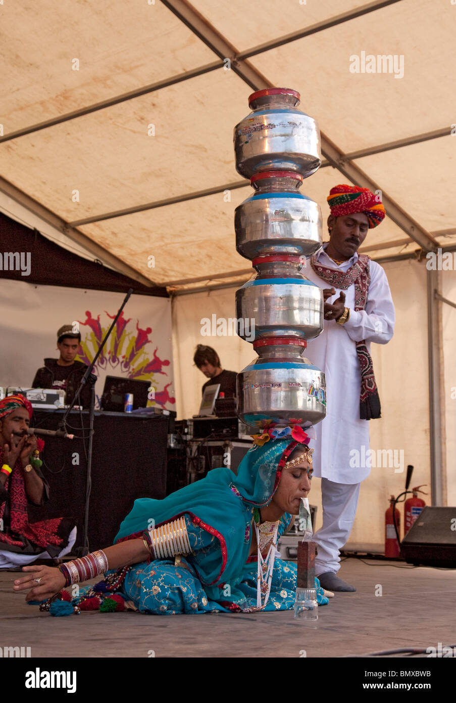 Rajasthani Bhavai Tänzerin nimmt Rupie Hinweis aus einem niedrigen Behälter während vier Töpfe /charis auf dem Kopf balancieren; Glasgow Stockfoto