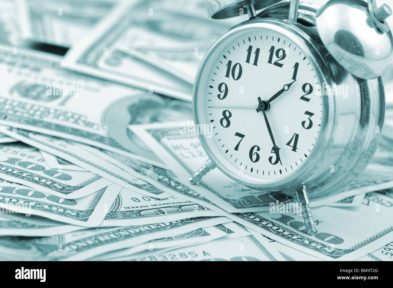 Zeit - Geld. Business-Konzept. Analoge Uhr auf einem Haufen Papier-Dollar. Blauton Stockfoto