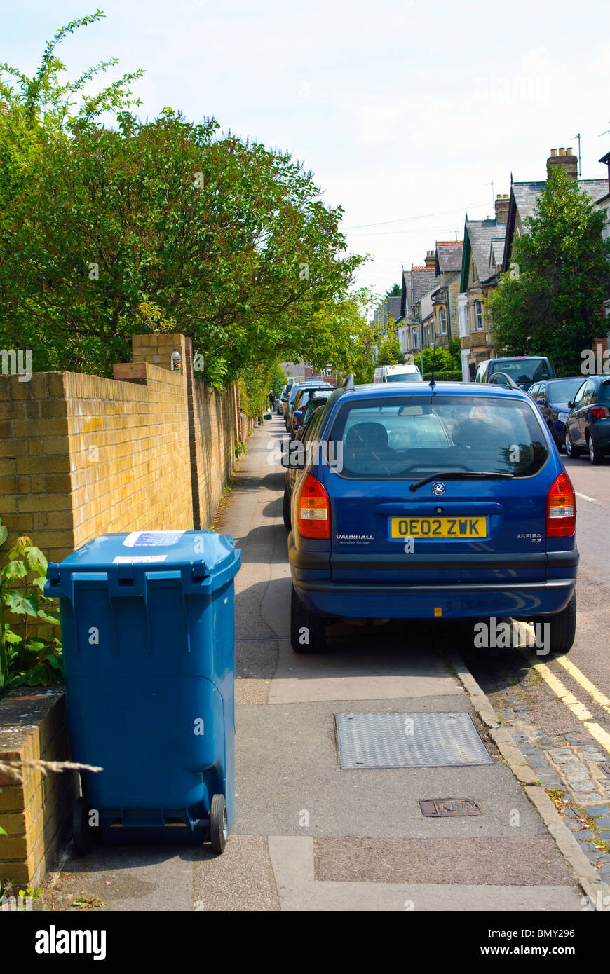 Autos und Wheelie Lagerplätze auf dem Fußweg geparkt sind ein Hindernis für Fußgänger in Oxford. Stockfoto