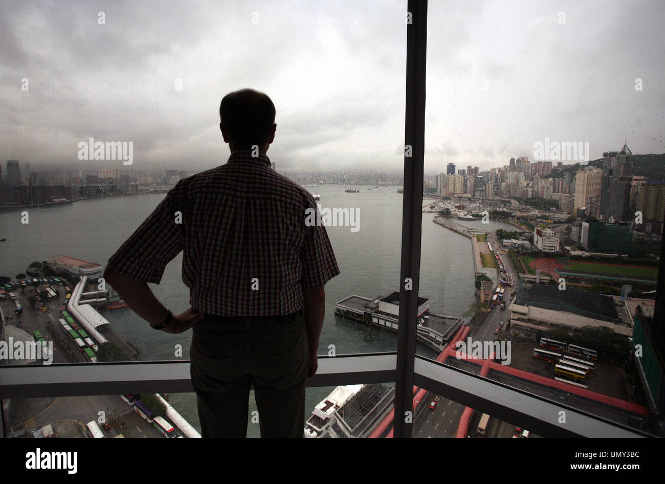 Ein Mann auf der Suche bei schlechtem Wetter durch ein Fenster, Hong Kong, China Stockfoto