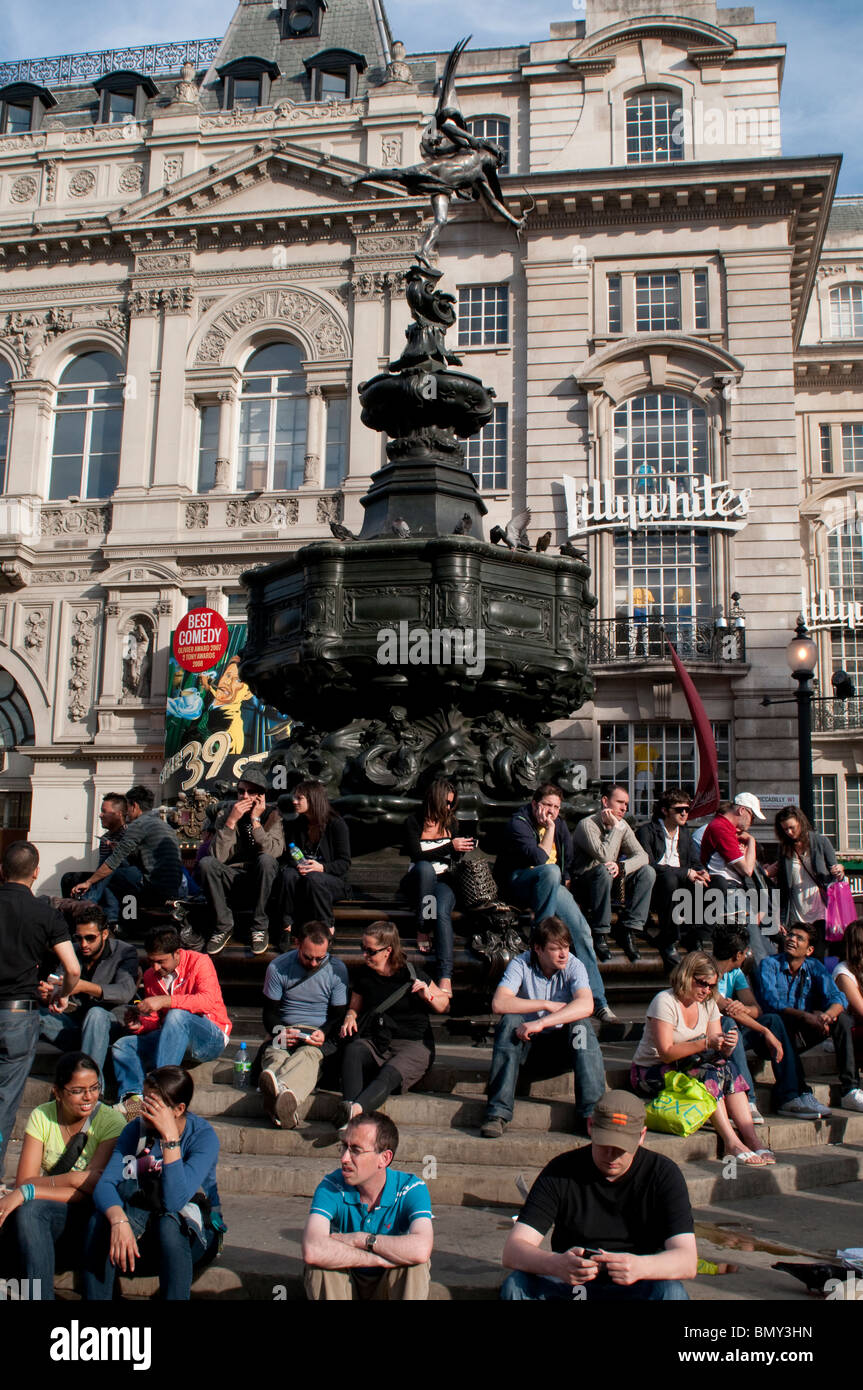 Leute sitzen herum und Eros-Statue am Piccadilly Circus, London W1, UK Stockfoto