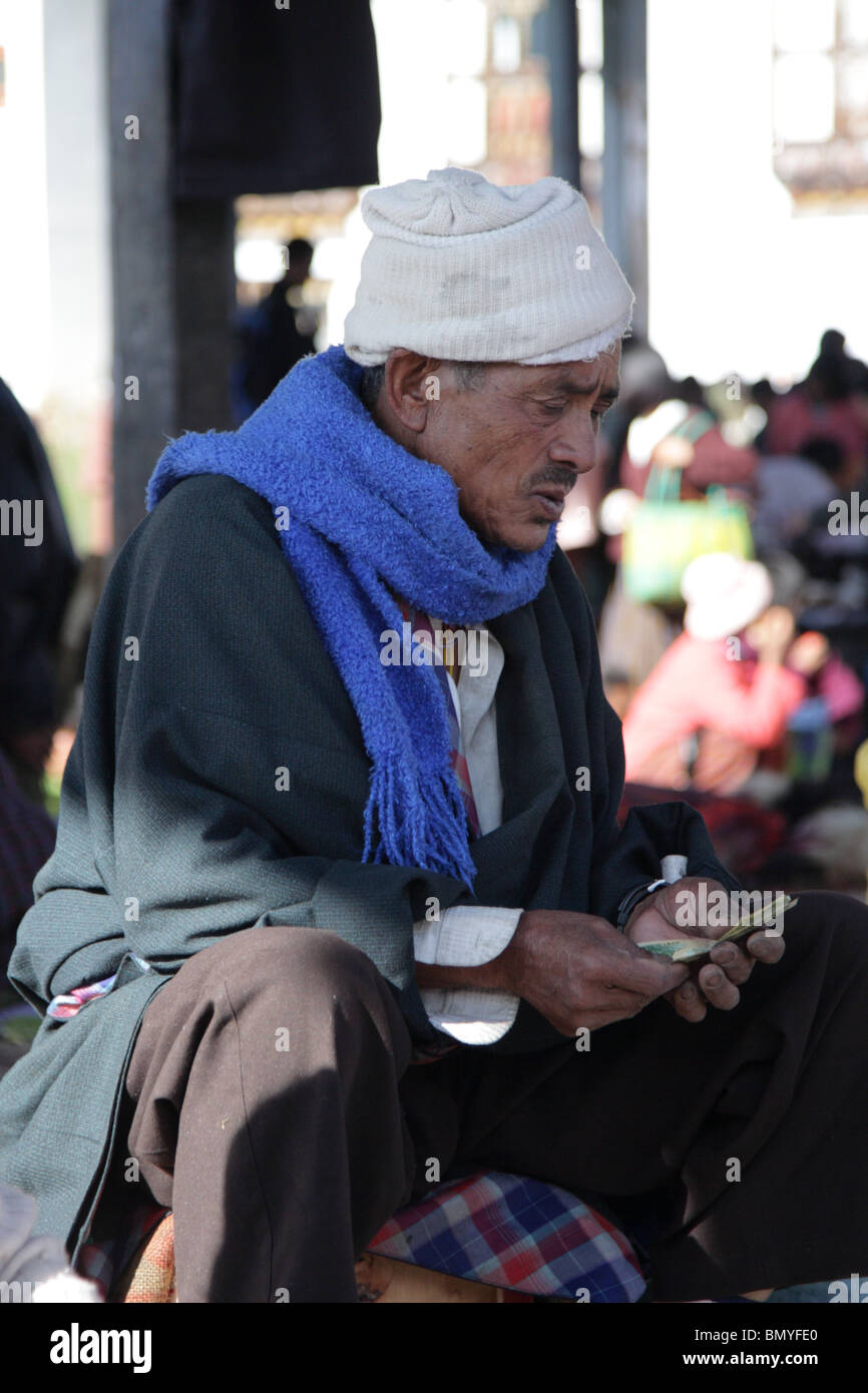 Ein Markt-Händler sorgfältig zählen sein Geld in Paro, Bhutan. Stockfoto