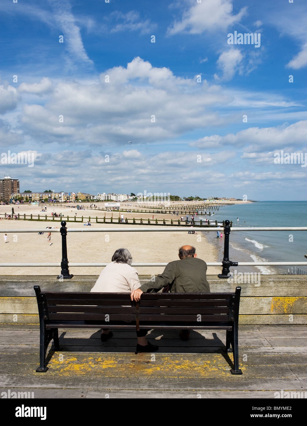 Zwei Menschen sitzen auf einer Bank mit Blick auf East Beach in Littlehampton in West Sussex.  Foto von Gordon Scammell Stockfoto