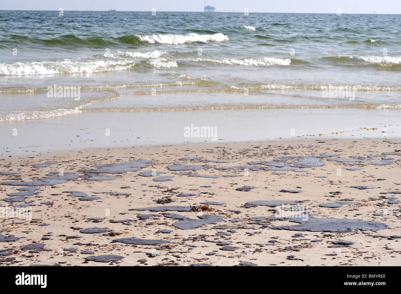 Ölpest am Strand mit off Shore Bohrinsel im Hintergrund. Stockfoto